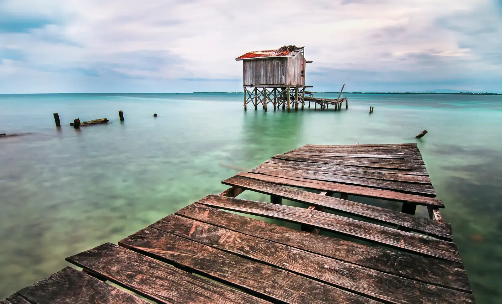 Wooden swimming dock over turquoise water on a Belize caye, the typical way islanders reach swimming depth