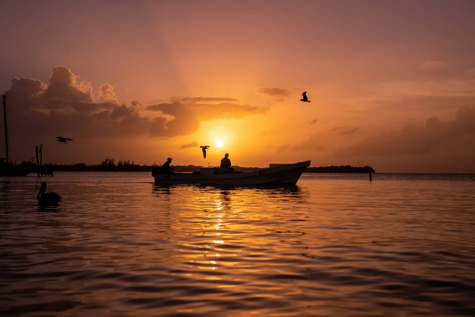 Boat silhouetted against a Caribbean sunset off Caye Caulker, Belize