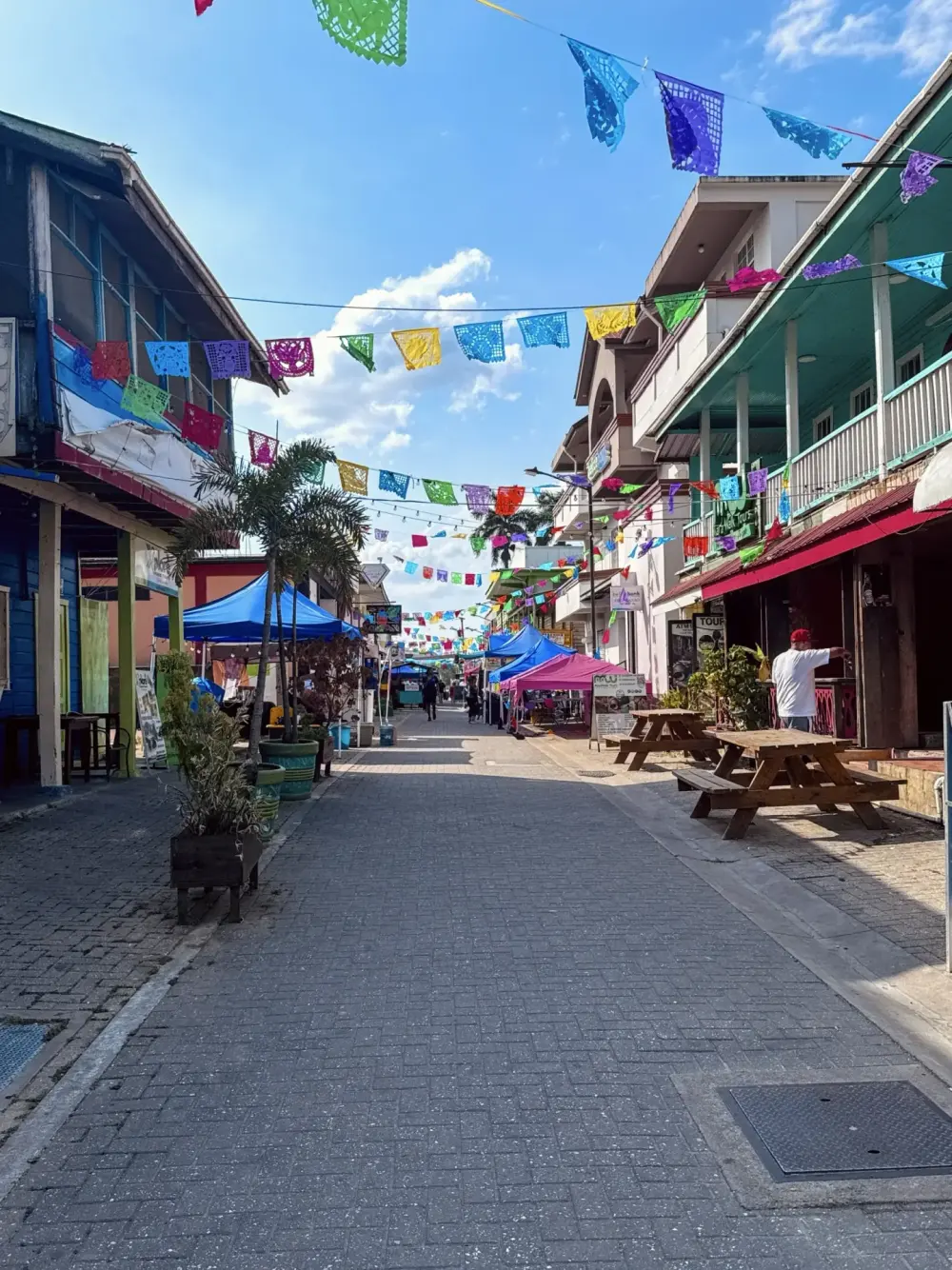 Papel picado bunting strung above Burns Avenue in San Ignacio, with tables set out along the street