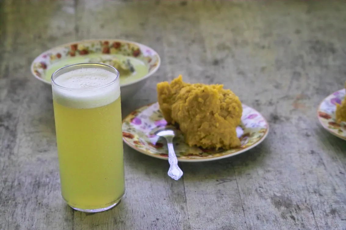 Garifuna hudut, a mound of mashed plantain, with coconut fish broth and a glass of juice in Belize
