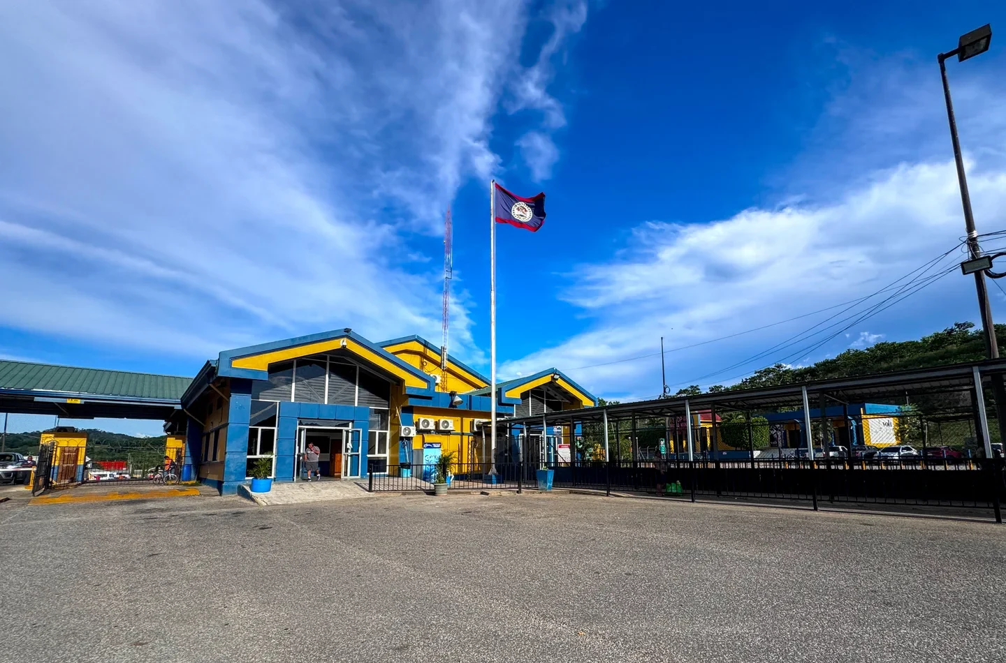 The Belize flag flying over the yellow and blue border station at Benque Viejo del Carmen, the western land crossing to Melchor de Mencos, Guatemala