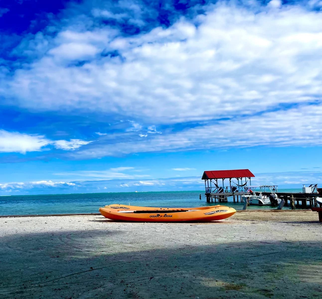 An orange kayak on the beach at Anchorage Beach Resort with the resort's dock and boats in the background