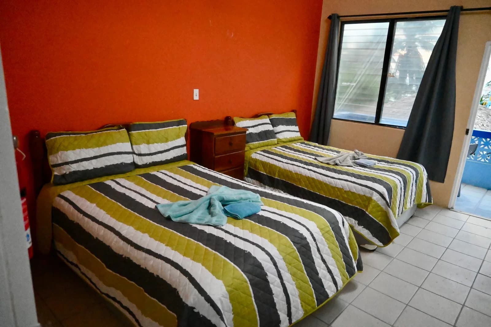 Guest room at Anchorage Beach Resort with two double beds, striped bedspreads, and air conditioning