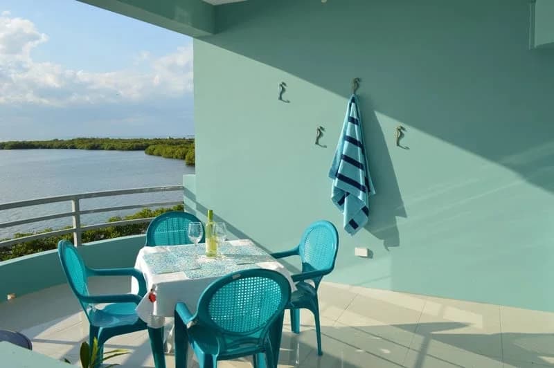 A west verandah at Bay Towers with a dining table set for two, looking over the water and mangroves of Caye Caulker's leeward side