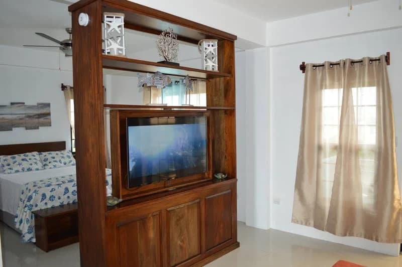Suite living area at Bay Towers with a hardwood entertainment unit dividing the bedroom