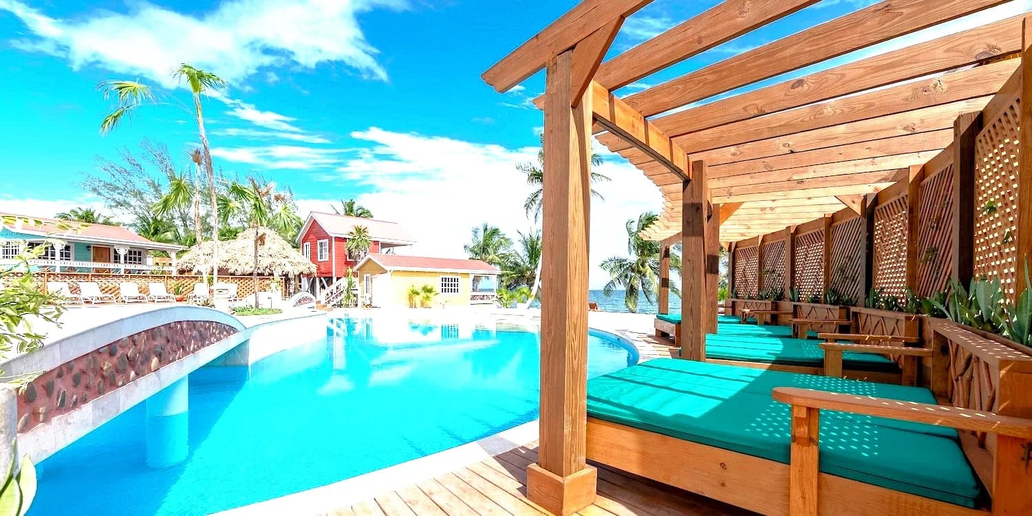 Shaded daybeds beside the main pool at Beaches and Dreams resort in Hopkins, Belize