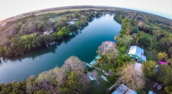 Aerial view of Belize River Lodge on a bend of the Belize Olde River near Ladyville, with skiffs lined up along the bank