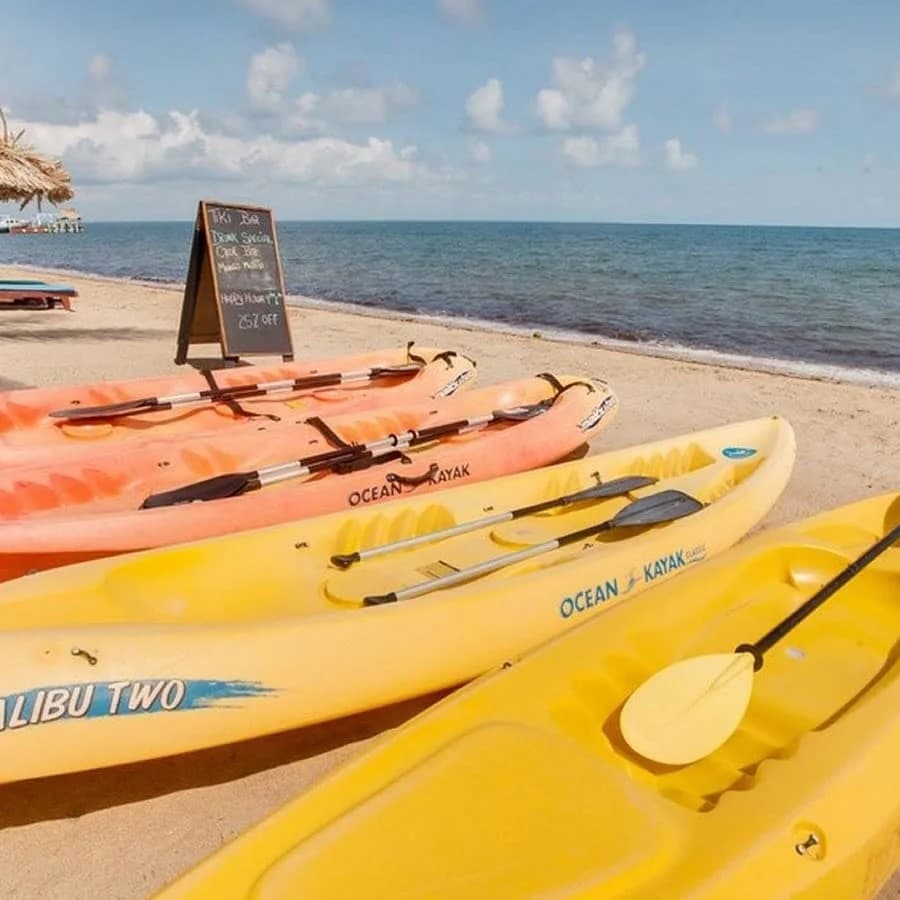 Colorful kayaks lined up on the beach at Belizean Dreams Resort, Hopkins Village