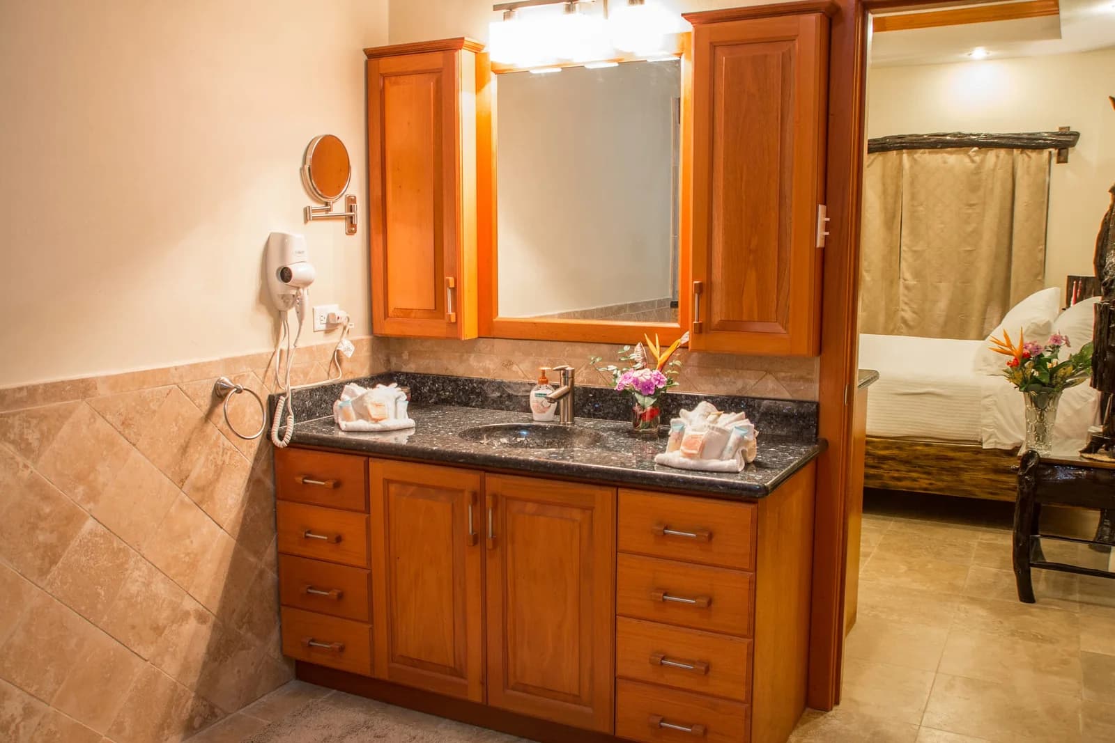 Bathroom with wood cabinetry and granite countertop in a guest room at Black Orchid Resort.