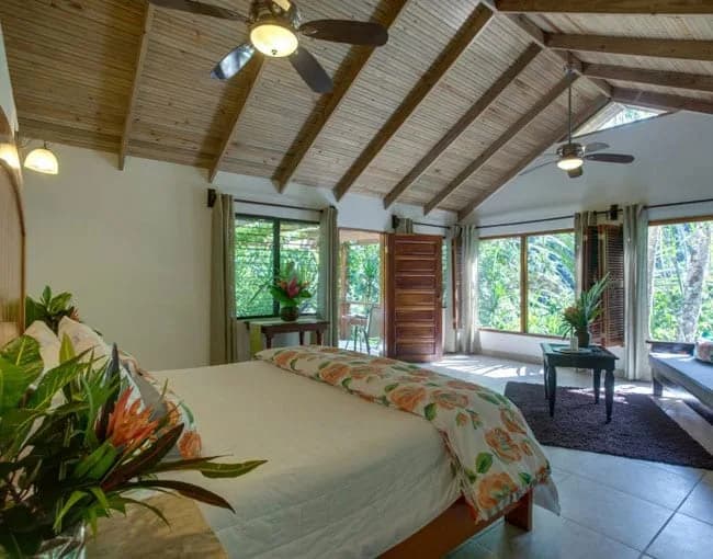 Bedroom in a Black Rock Lodge Riverview Deluxe cabin with vaulted wood-beamed ceiling and jungle-view windows