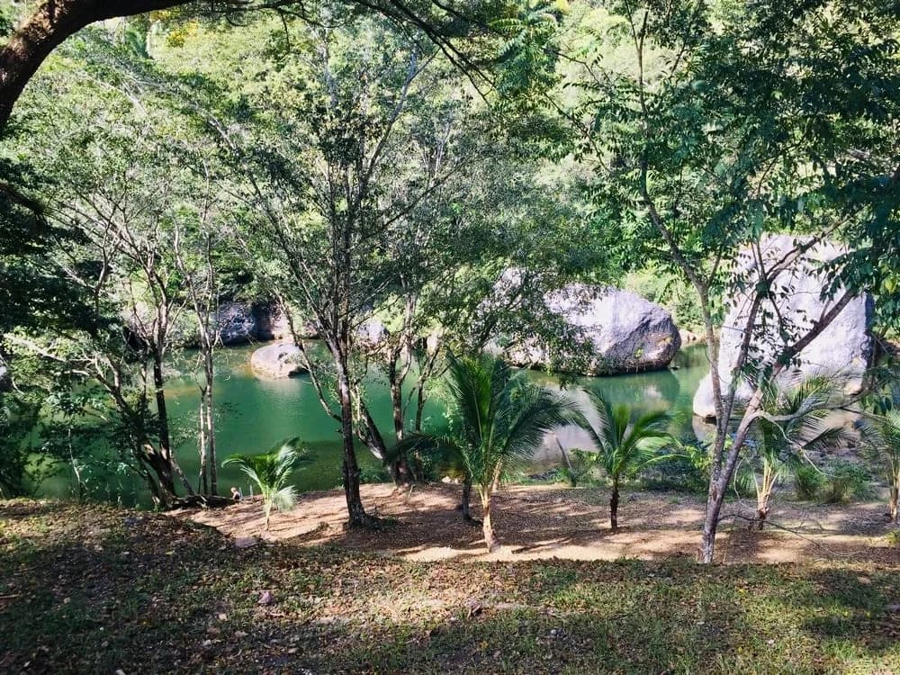 Natural swimming hole ringed by large black boulders on the Macal River at Black Rock Lodge