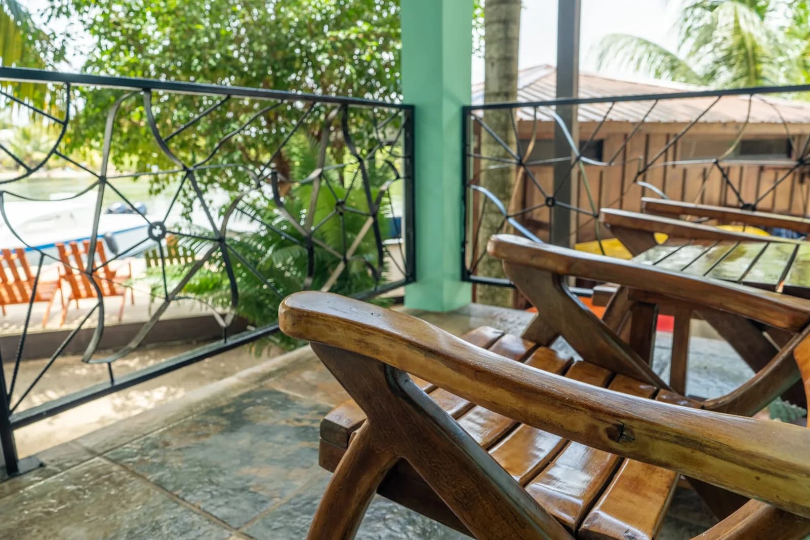 Wooden chairs on the covered balcony of the Good Times and Tan Lines apartment at Captain Jak's, with the lagoon dock below