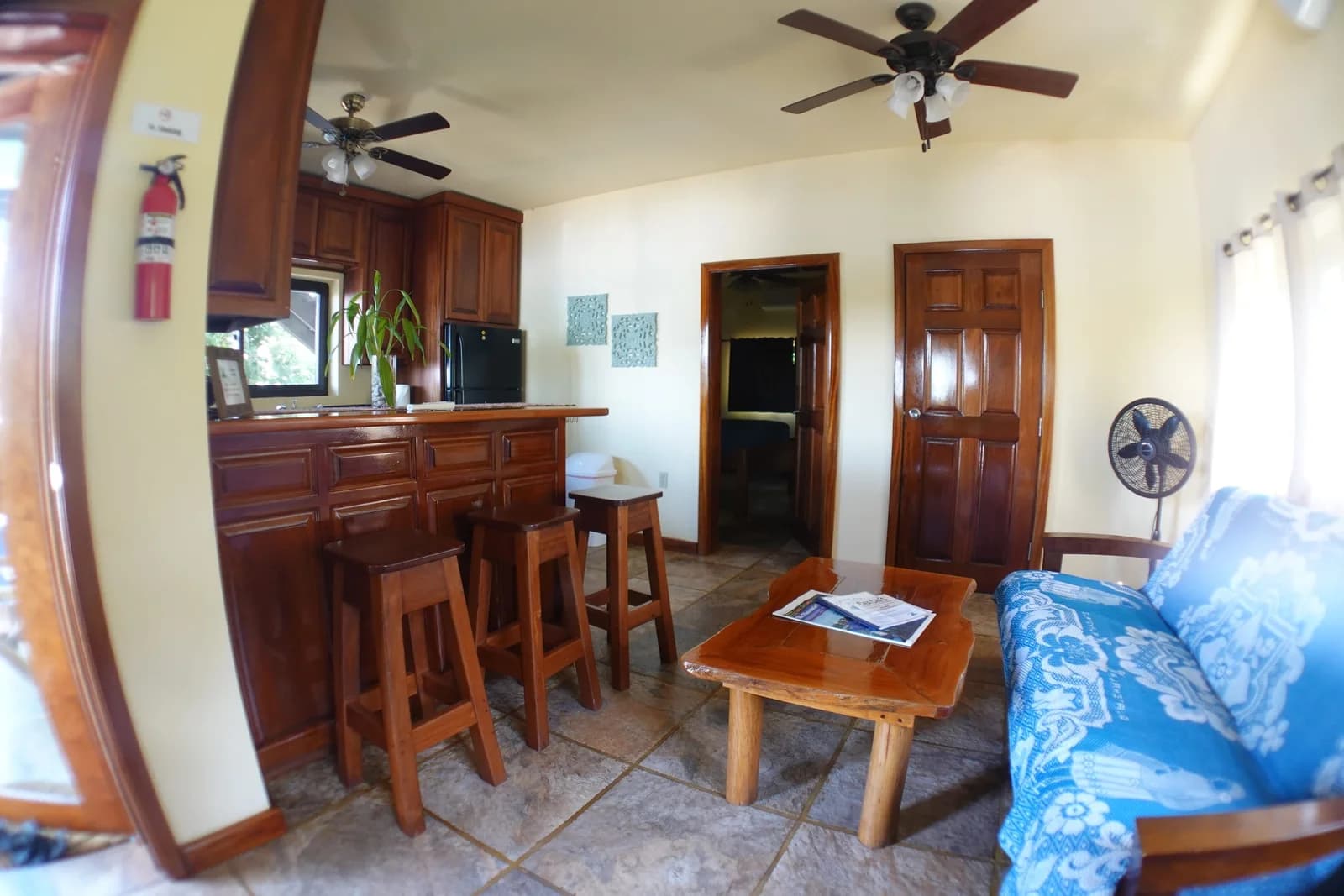 Living room of a Captain Jak's lagoon apartment with a hardwood kitchen bar, stools and a futon