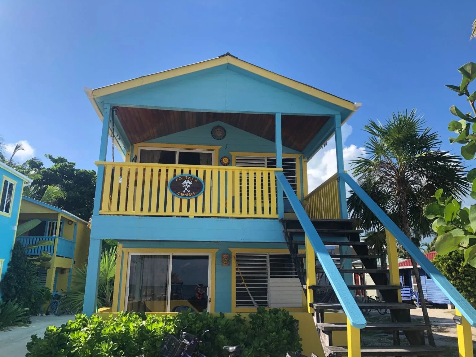 Blue and yellow Colinda Cabanas beachfront suite building with balcony, stairs, and property signage