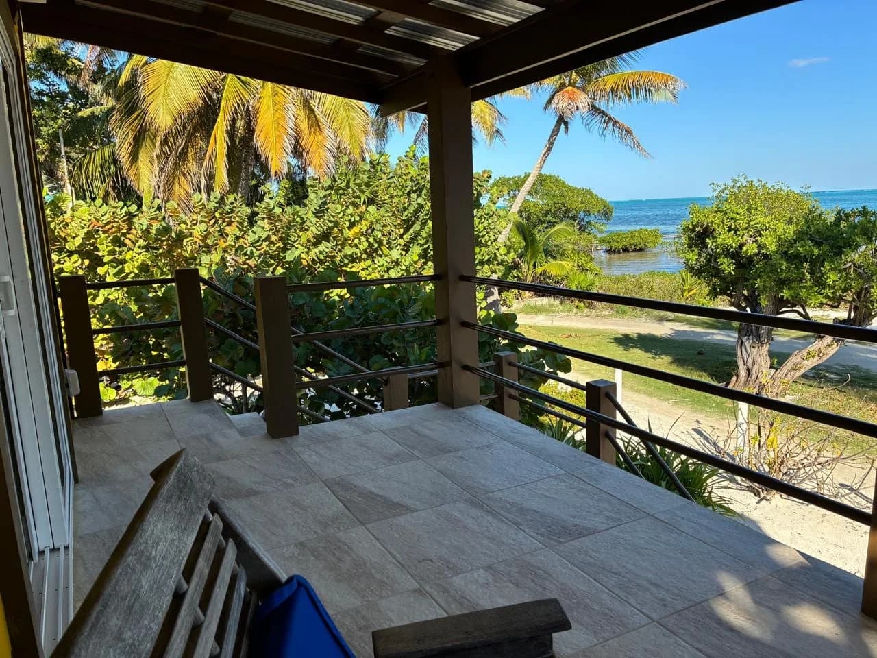 Covered oceanview patio and terrace of the Private Beach House, with palm trees and the Caribbean Sea beyond