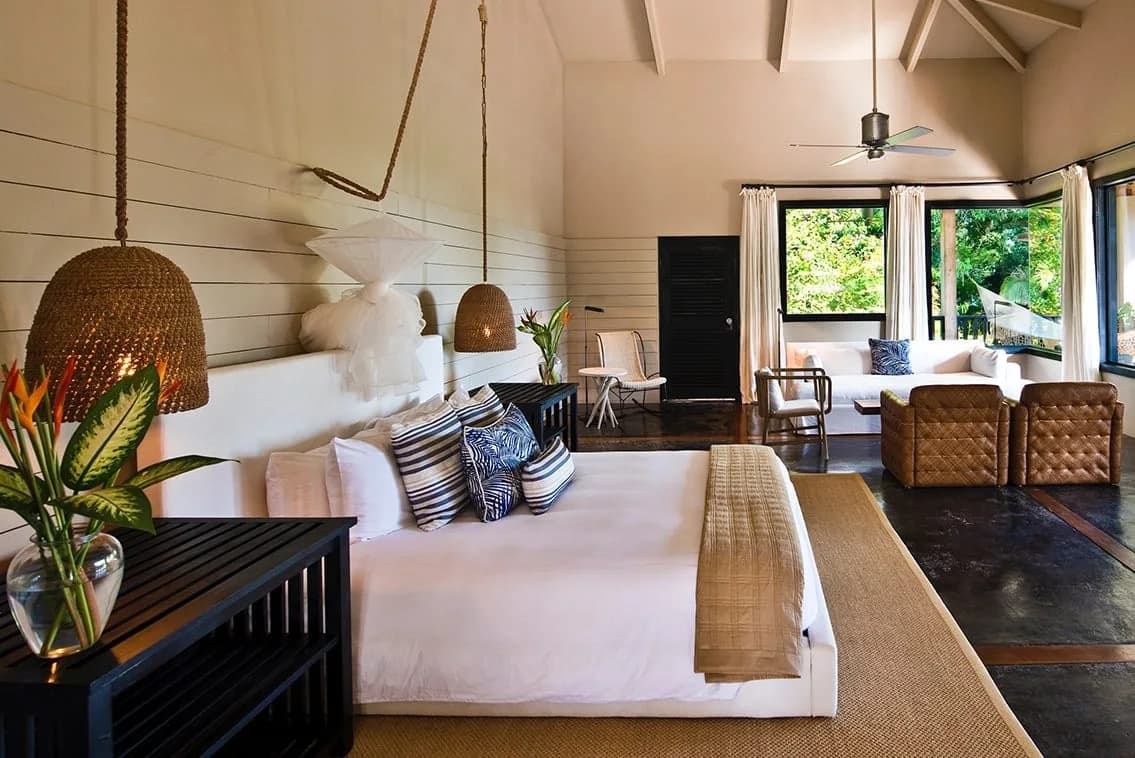Interior of a Signature Canopy Suite bedroom at Copal Tree Lodge with king bed, seating area, and floor to ceiling jungle views
