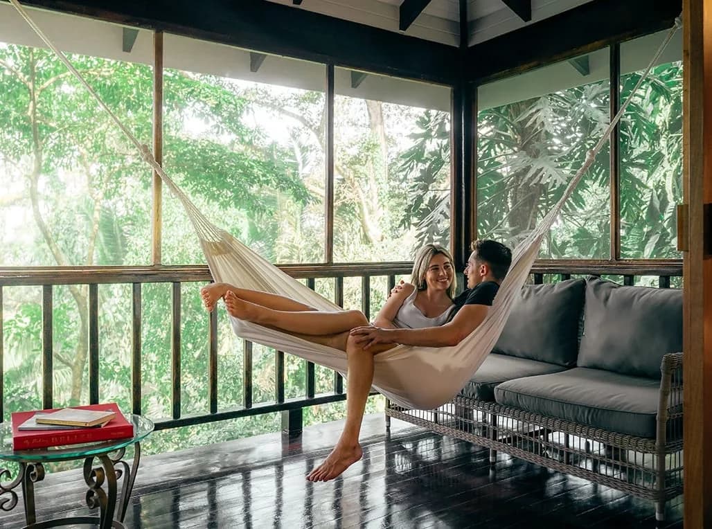 Couple relaxing in a hammock on a screened suite balcony overlooking the rainforest at Copal Tree Lodge