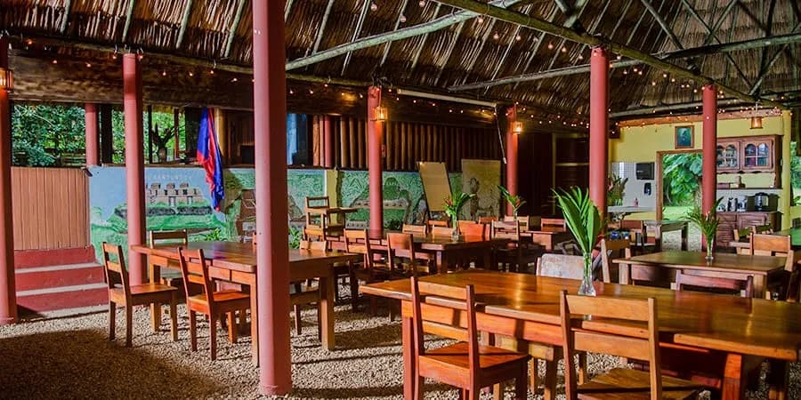 Open-air, thatched-roof dining pavilion set with wooden tables at Crystal Paradise Resort