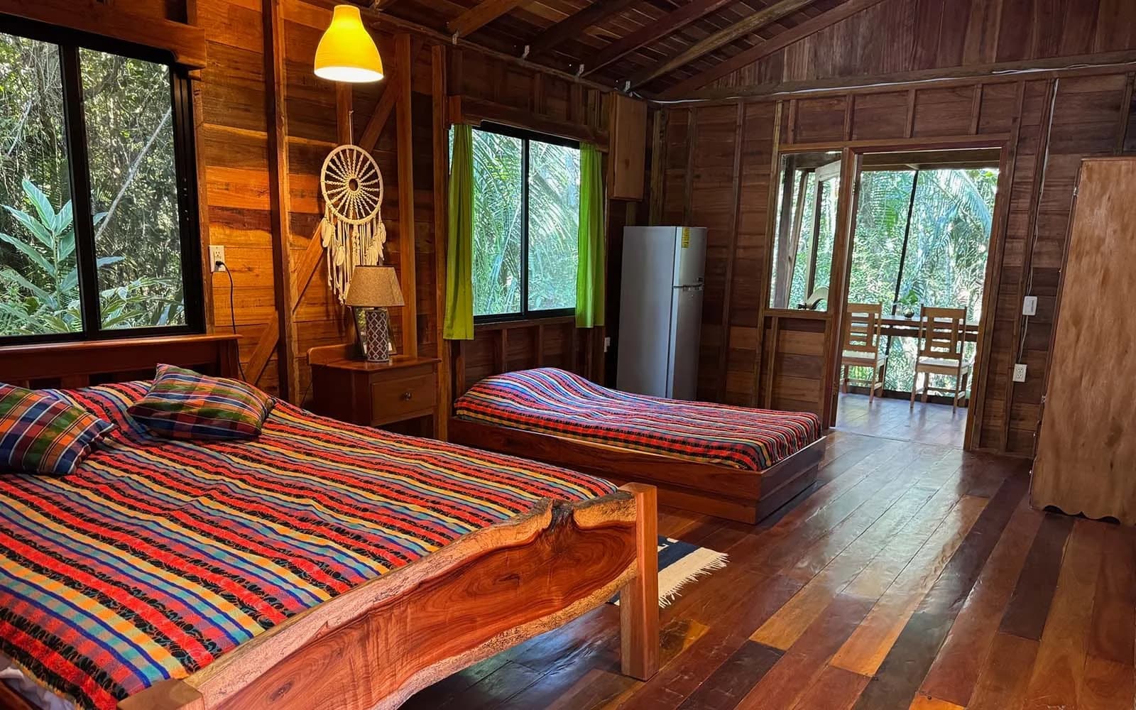 Green Jay Cabin bedroom with wood interior and a private screened porch overlooking the rainforest