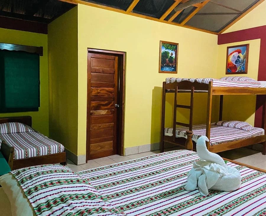 Family-style cabana interior with a queen bed and bunk beds, decorated with local Belizean textiles