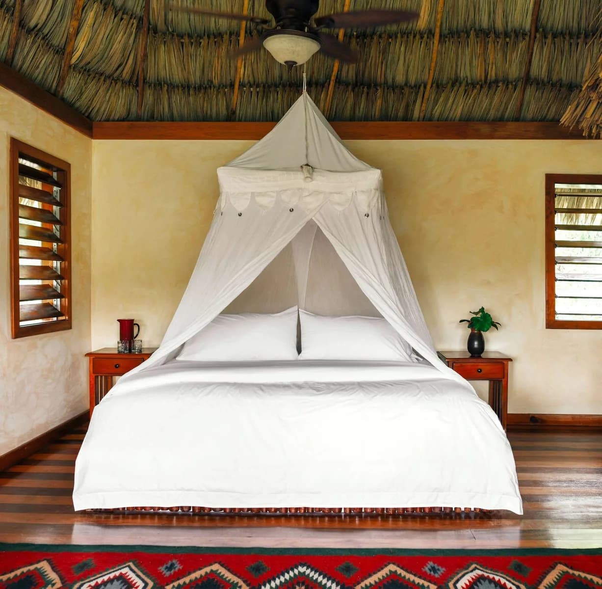 Canopy bed with mosquito net inside a thatched-roof suite at Gaia Riverlodge