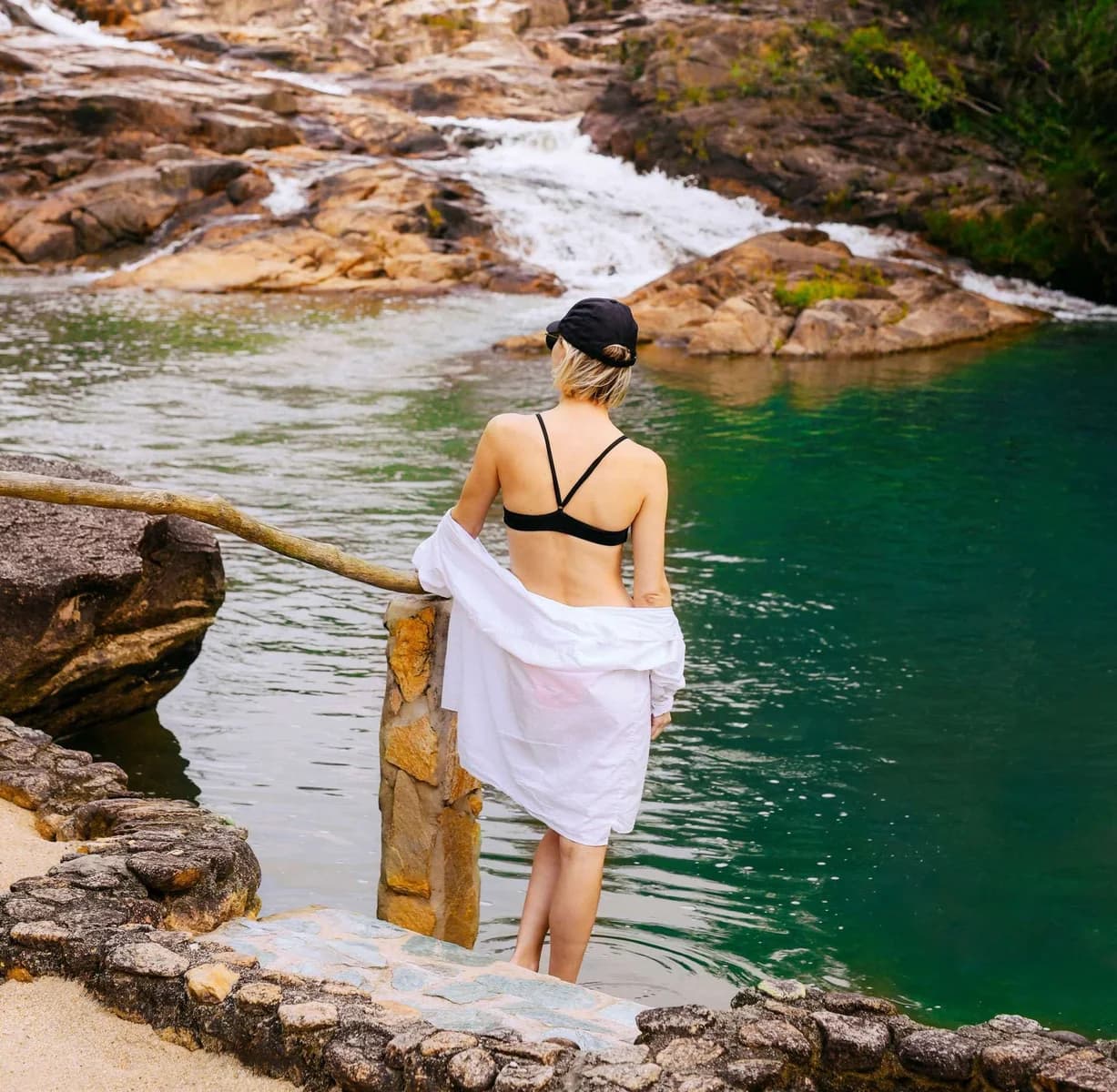 Guest wading into a natural spring-fed swimming pool below the Five Sisters Falls at Gaia Riverlodge