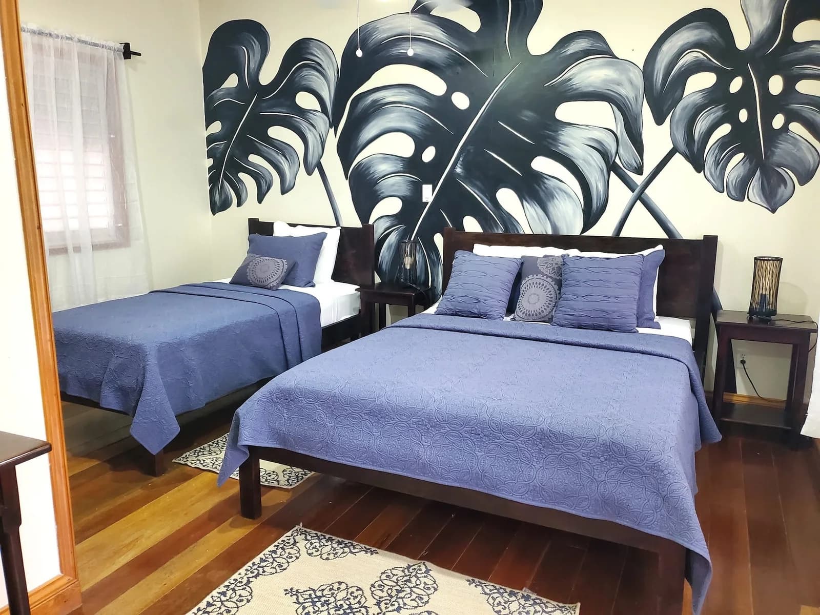 Duplex Cottage bedroom at Hickatee Cottages with a hand-painted monstera leaf mural and twin beds