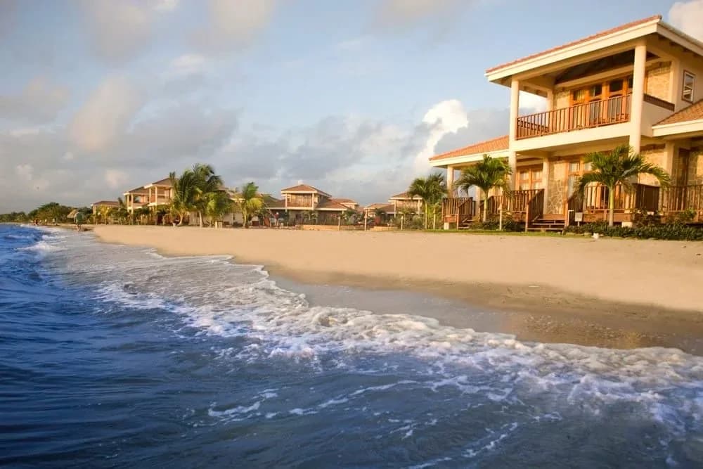 Row of Hopkins Bay Belize beach houses along the shoreline at golden hour, viewed from the sand