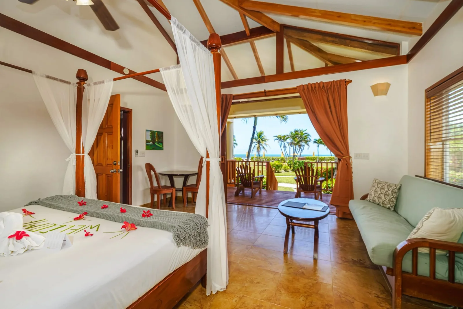Interior of a Hopkins Bay Belize one bedroom suite with a four-poster bed and an ocean-view balcony