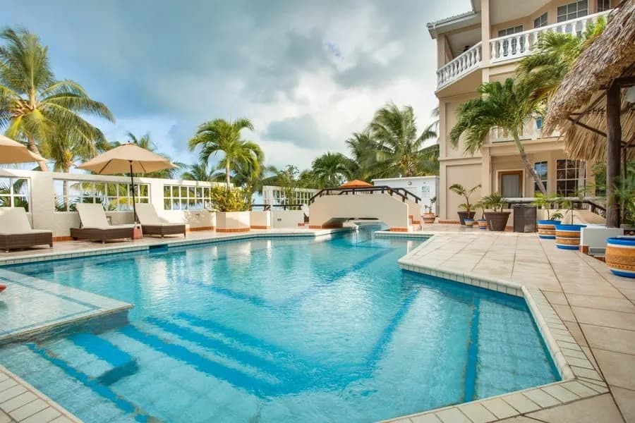 Freshwater swimming pool with steps and loungers beside the three-story inn, Iguana Reef Inn, Caye Caulker, Belize