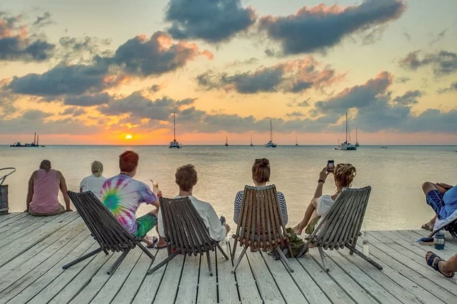 Guests watching the sunset from dock chairs over the water at Iguana Reef Inn, Caye Caulker, Belize