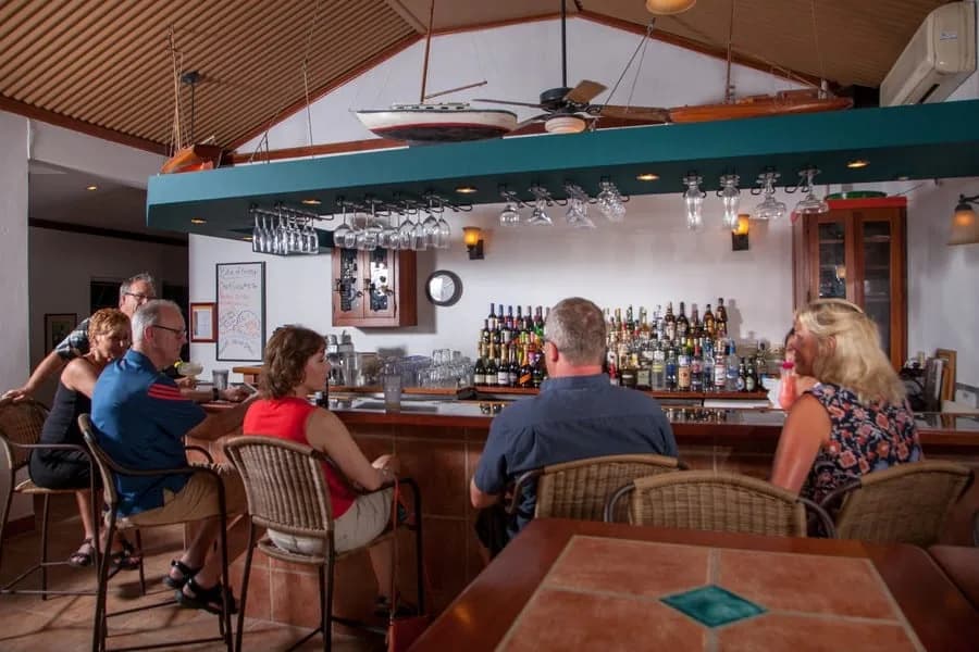 Guests seated at the indoor bar with a full liquor display, Iguana Reef Inn, Caye Caulker, Belize