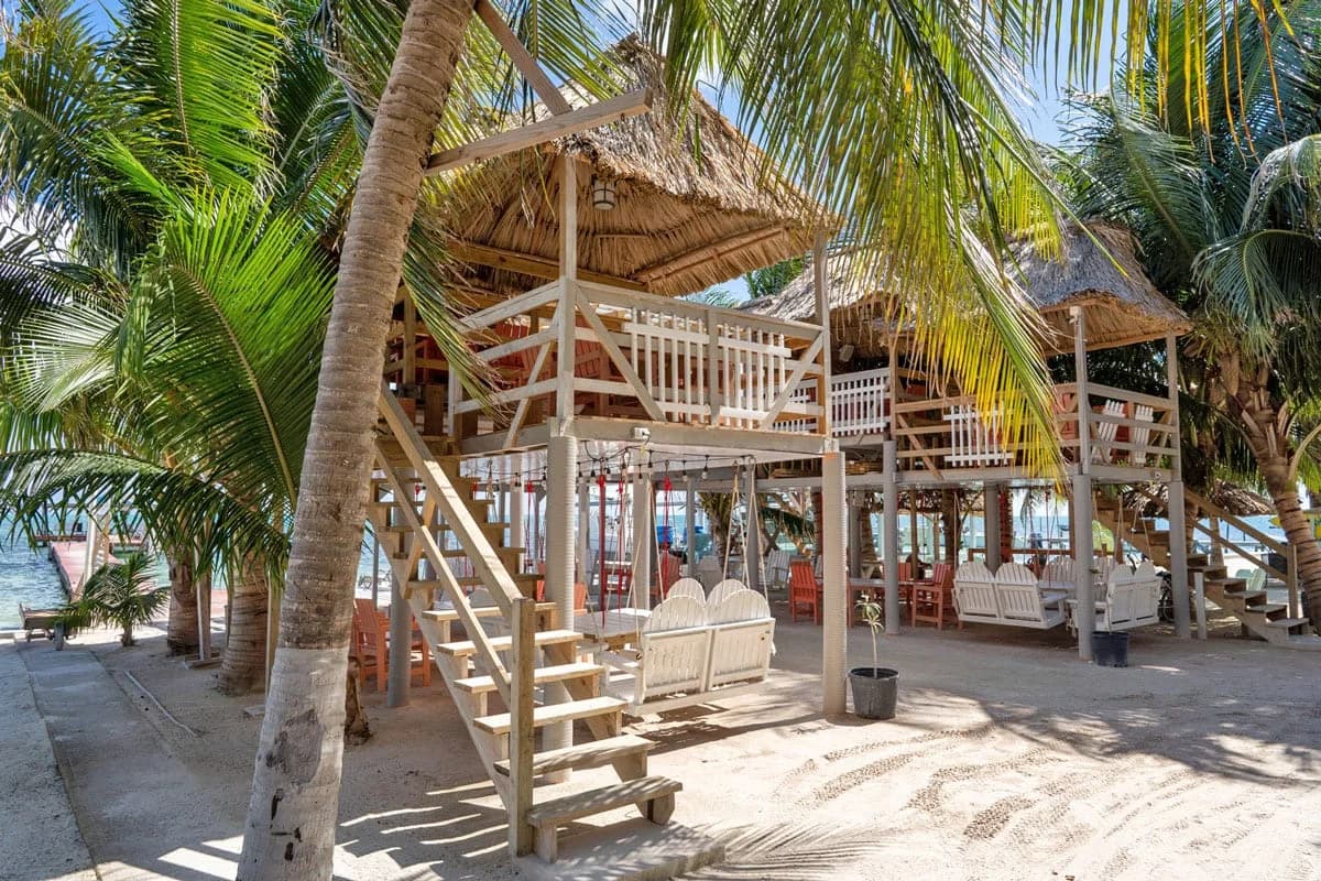Two-story thatched-roof beach bar structure at Island Magic Beach Resort surrounded by palm trees and dock