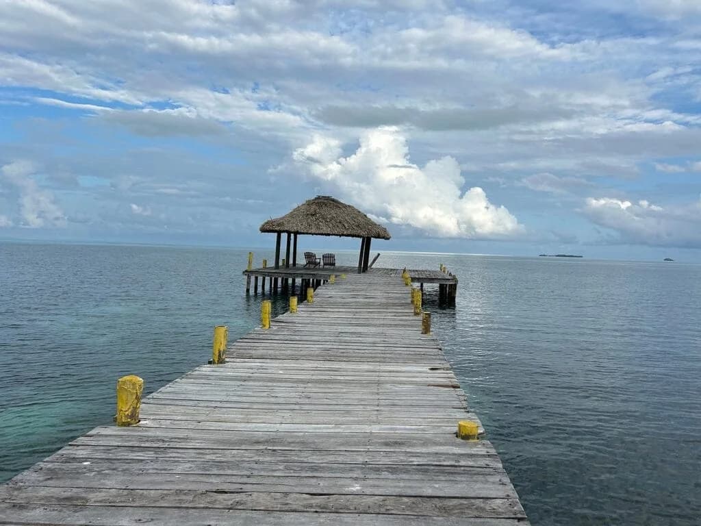 Wooden pier leading to a thatched palapa over the water at Itza Resort, Long Caye, Lighthouse Reef Atoll, Belize