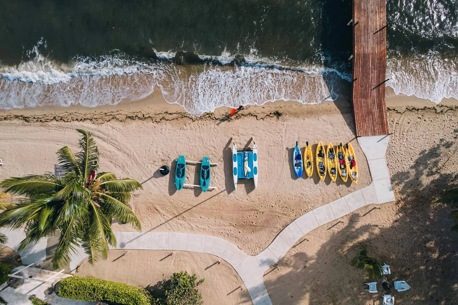 Aerial view of the private beach at Jaguar Reef Lodge & Spa with kayaks, paddleboards, and a catamaran lined up for guests