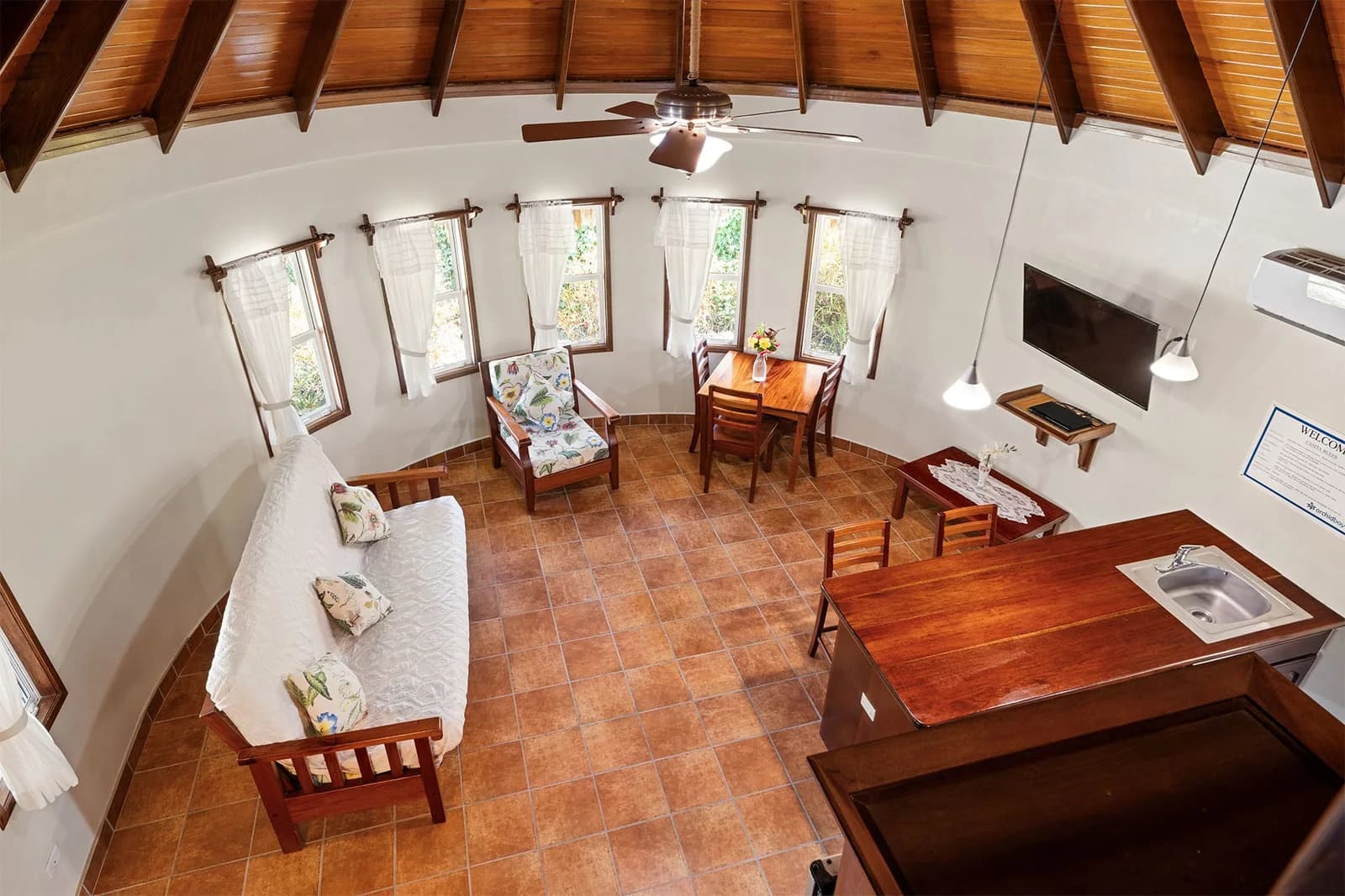 Living area inside an Orchid Bay Resort condo, with a palapa-style thatched ceiling, wood shutters and rattan furniture