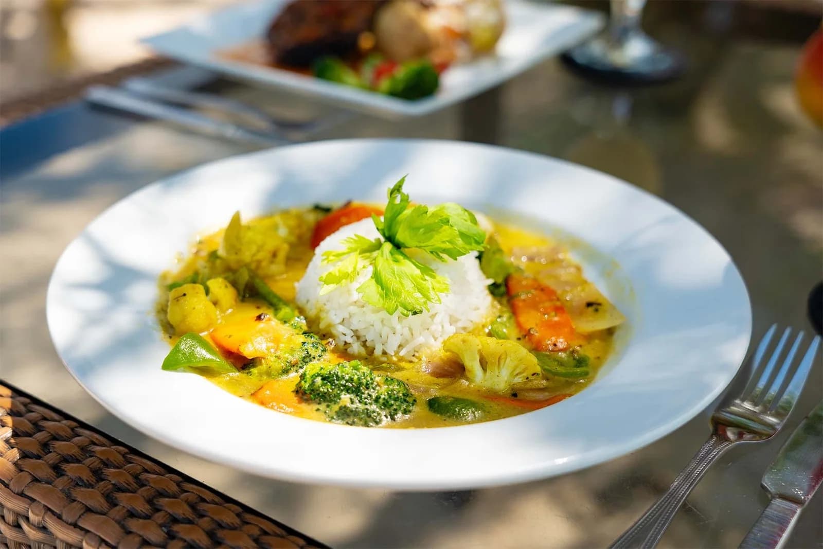 A plated seafood curry with rice served on the terrace of Orchid Bay Resort's Tradewinds Restaurant