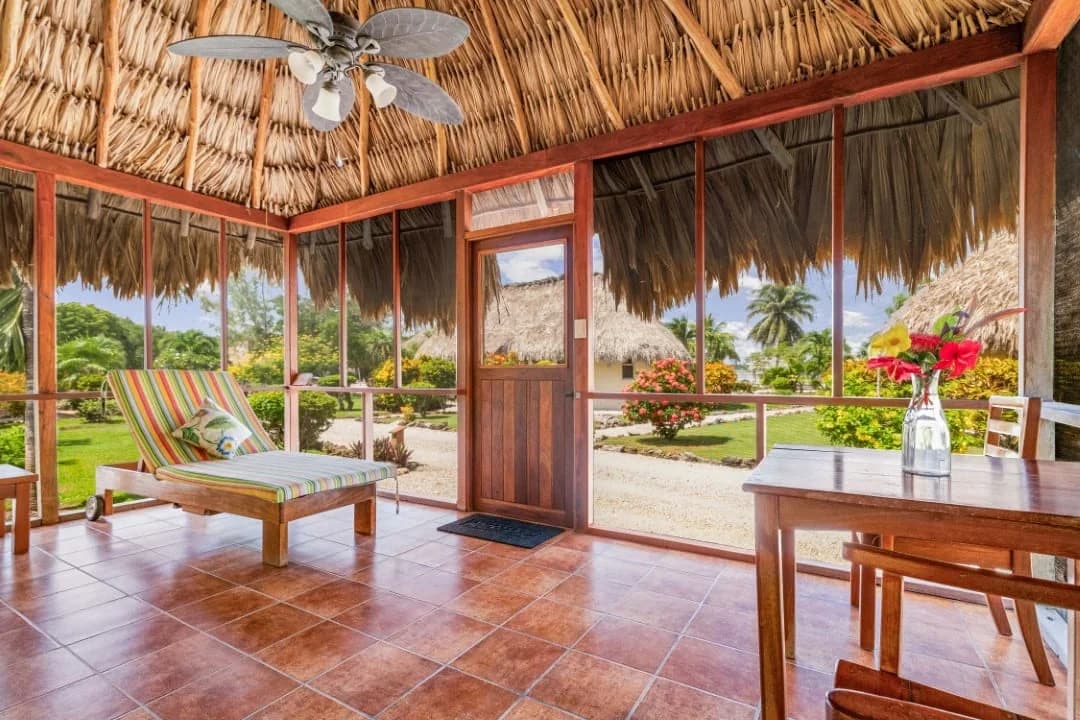 Screened porch of an Orchid Bay Resort casita looking out over landscaped grounds and neighboring thatched-roof cabanas