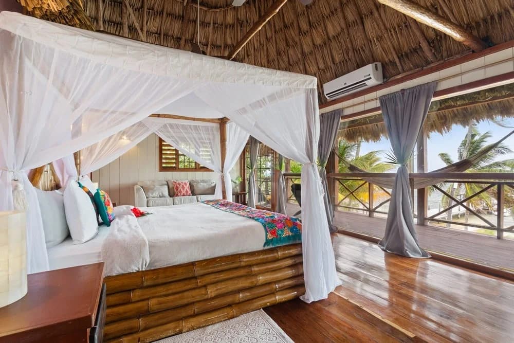 Canopy bed in the Honeymoon Suite at Portofino Beach Resort with ocean-view balcony beyond