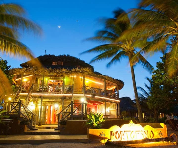 Portofino Beach Resort's thatched restaurant and bar building lit up at dusk