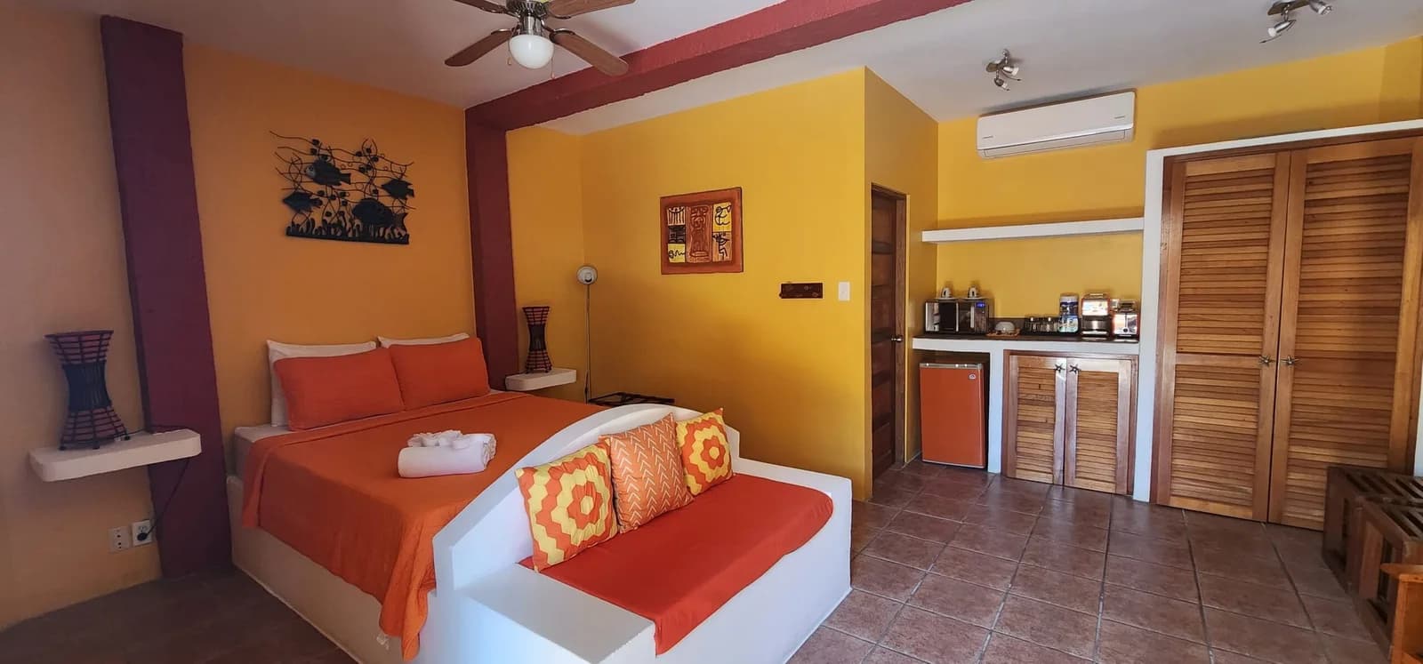 Colorful cabana room in golden yellow tones at Seaside Cabanas with a kitchenette, mini fridge and daybed