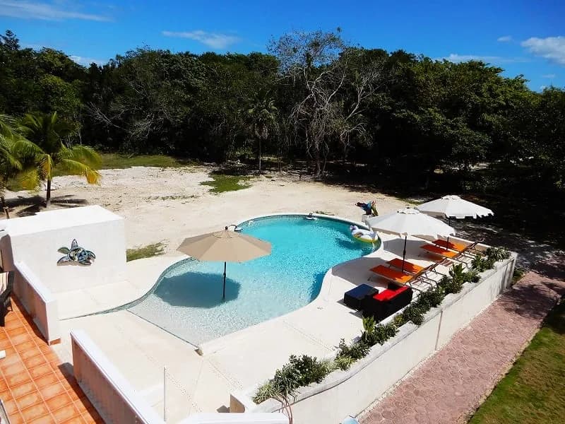 Aerial view of the swimming pool, sun umbrellas, and loungers at Serenity Sands Bed & Breakfast in Corozal, Belize