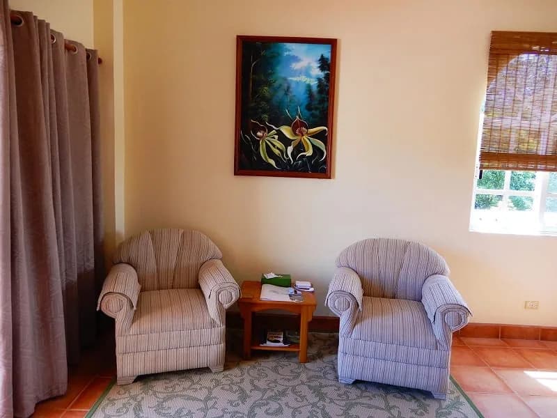 Guest bedroom with wooden headboard, soft linens, and orchid artwork at Serenity Sands Bed & Breakfast