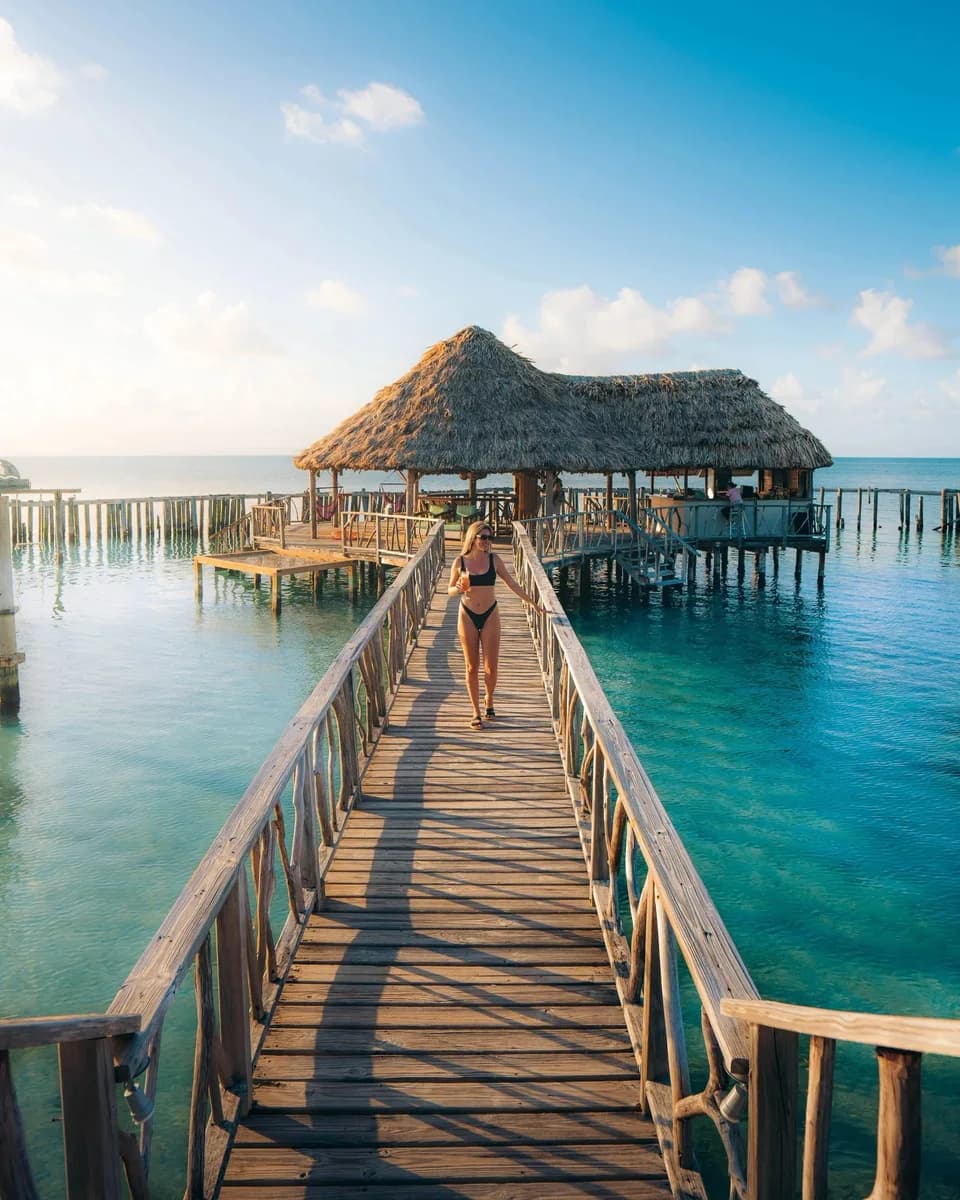 Overwater Starfish Bar at Thatch Caye Resort with its thatched roof perched over turquoise water
