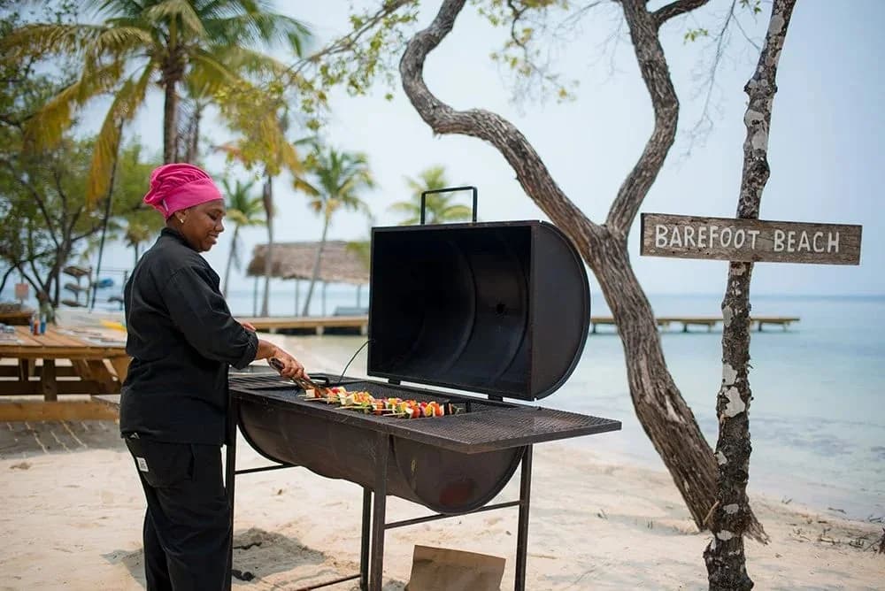 Private chef grilling a beach barbecue on Barefoot Beach at Thatch Caye Resort