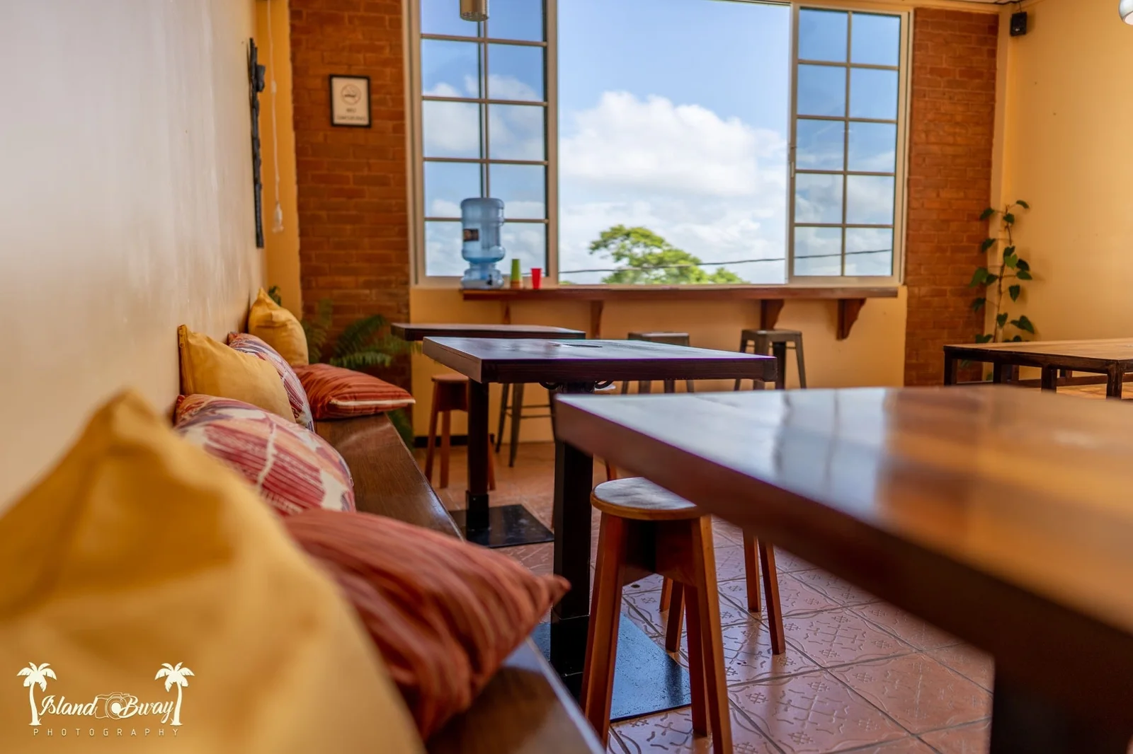 Rooftop common lounge with cushioned bench seating and large windows at Yellow Belly Backpackers, San Ignacio, Belize