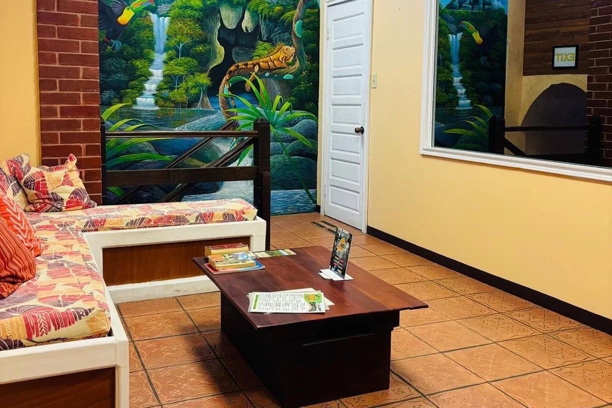 Colorful lounge and reception area with a hand painted jungle mural at Yellow Belly Backpackers hostel in San Ignacio, Belize
