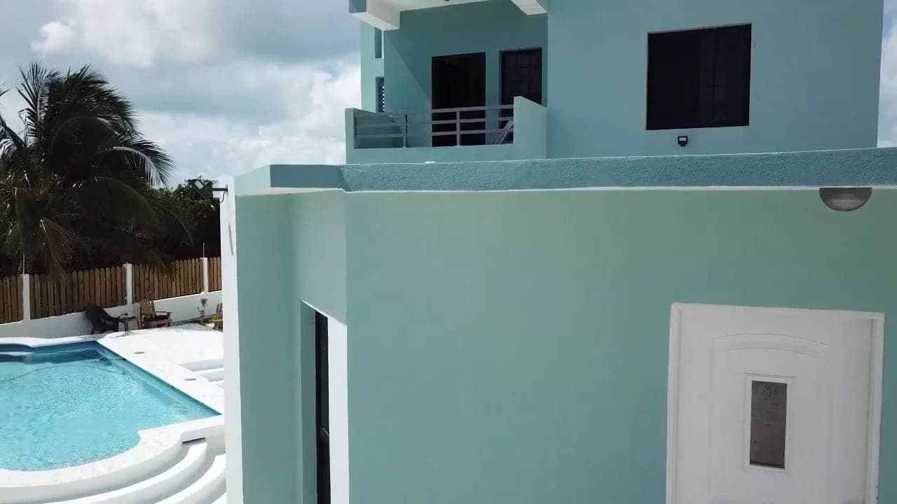 The aqua tower of Bay Towers Caye Caulker with its rooftop terrace and balconies, seen beside the pool