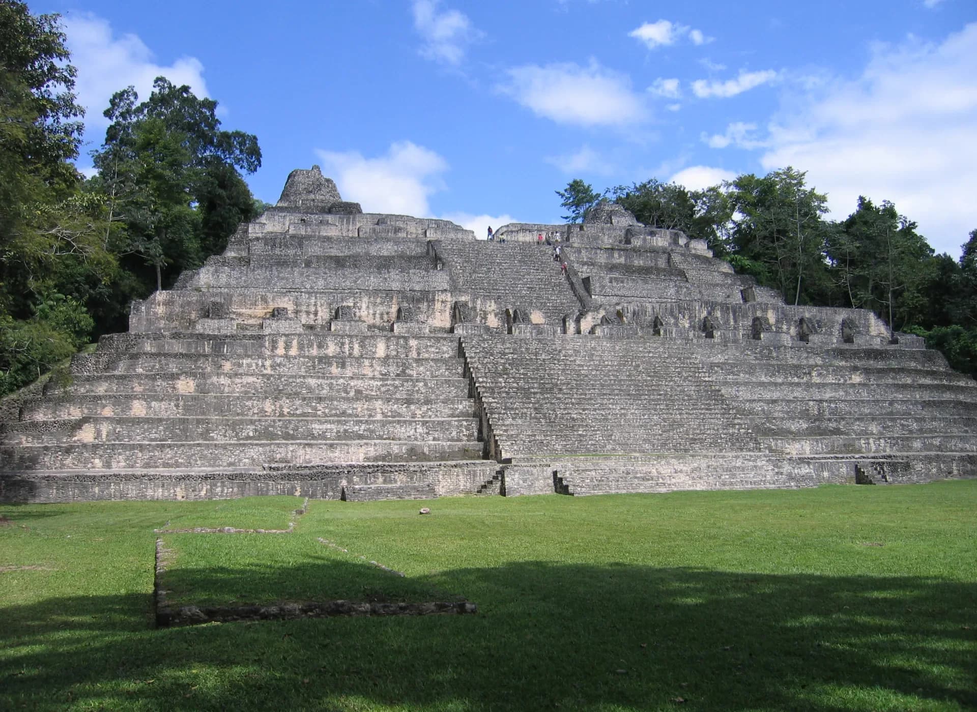 Frontal view of the stepped Caana temple complex at Caracol, Belize, beneath a blue sky.