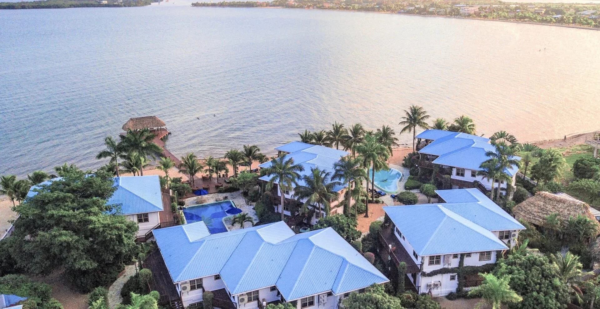 Aerial view of Chabil Mar Villas' cluster of blue-roofed beachfront villas, pool and private pier in Placencia, Belize